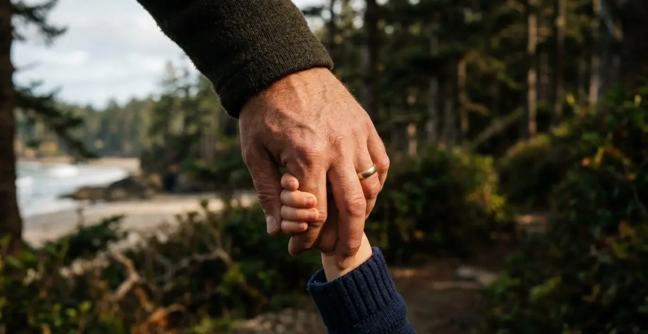 Une main d'adulte tenant la main d'un enfant, avec un arrière-plan flou de paysage landais.